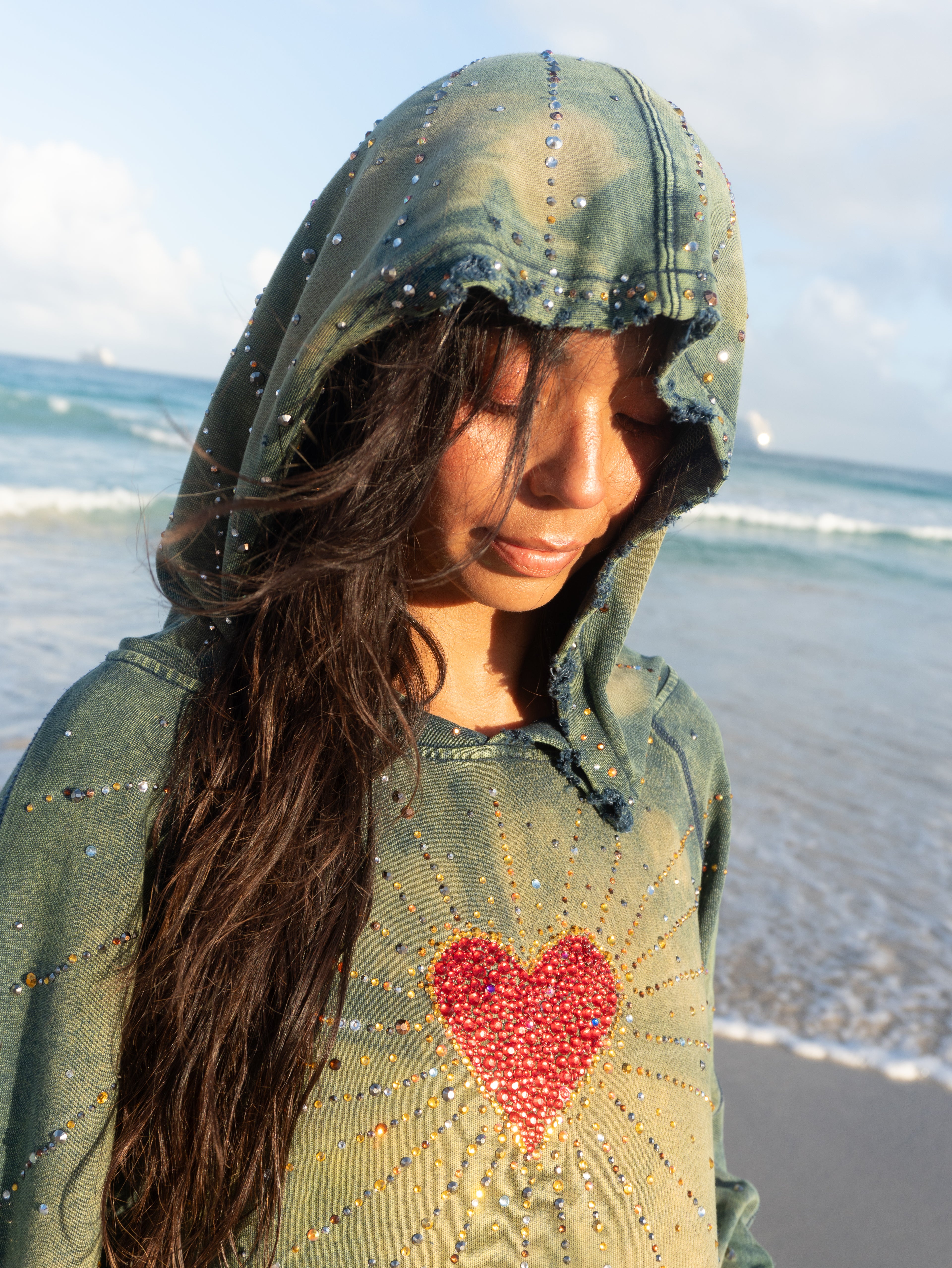 Close-up of the Unconditional Love oversized hoodie featuring rhinestone heart artwork, distressed details, and hand acid-washed fabric.
